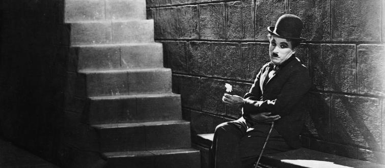 If you picture the classic, melancholic silhouette of "the tramp" wandering down a dusty path, which legendary filmmaker comes to mind?